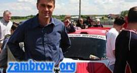 Krzysztof Hołowczyc na tle sportowego Peugeot-a 206, w którym zamontowany jest...